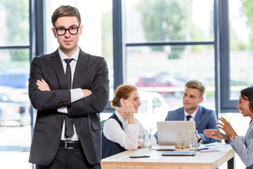 Confident businessman in front of his colleagues in modern office