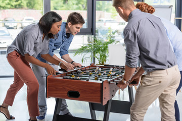 Young people playing table football in modern office
