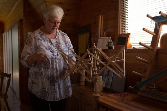 Senior woman using weaving loom at shop
