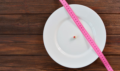 Tape measure and little sweeet cake on a white big plate, as a concept of health care and diet.