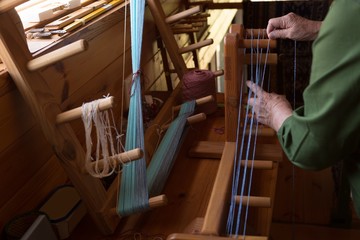 Senior woman weaving silk at shop
