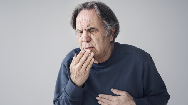 Elderly man coughing on isolated background