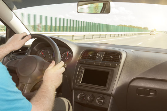 man driving a car. hands on the handlebars. on a background of a road in sunset sun. interior. Multimedia. Enjoyment from driving