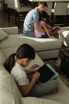 Girl using digital tablet with her father in living room