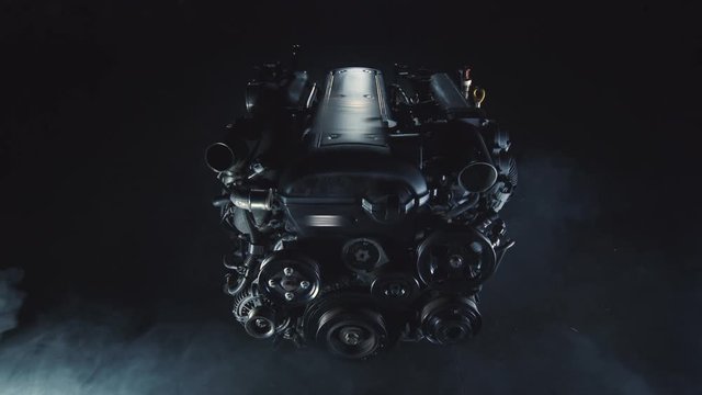 Modern repair of an automobile racing internal combustion engine in a technological repair shop. Fast Speed Mechanism in a dark room around a lot of smoke and gases. The concept of power and high-tech