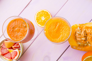 Healthy Food, Diet Concept. Fruit and Vegetable Smoothie assortment with pieces of fresh orange, pumpkin and grapefruit on pink wooden background, top view