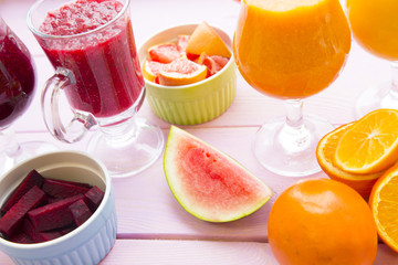 Fototapeta na wymiar Healthy Food, Diet Concept. Fruit and Vegetable Smoothie assortment with fresh oranges,chopped beetroot and cut grapefruit on pink wooden background, top view