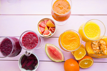 Fototapeta na wymiar Healthy Food, Diet Concept. Fruit and Vegetable Smoothie assortment with fresh lemos, oranges, beetroot, pumpkin and watermelon on pink wooden background, top view