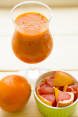 Fruit and Vegetable Smoothie, Healthy Food, Diet Concept. A glass of fresh smoothie, orange and cut grapefruit on a light wooden background