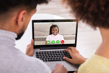 Fototapeta na wymiar Couple Video Conferencing With Daughter On Laptop