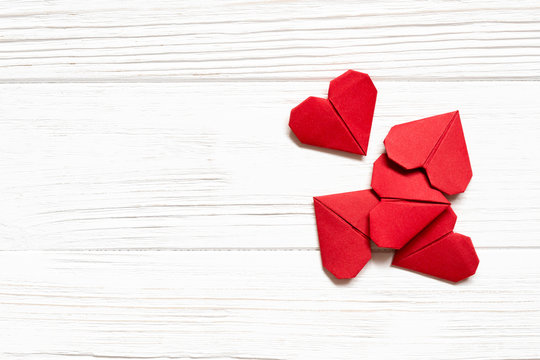 Red origami hearts on white wooden background. Copy space.
