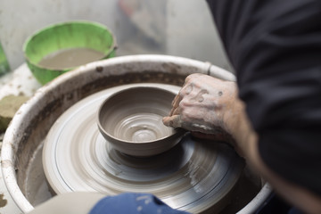 Artist makes clay pottery on a spin wheel