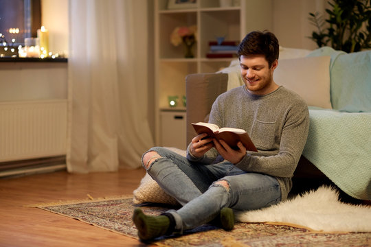 Happy Young Man Reading Book At Home