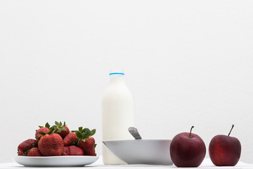 Composition with strawberries, red apples and milk on table
