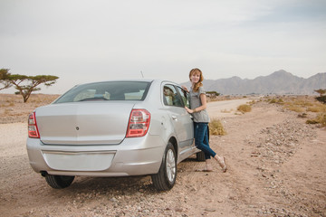 Fototapeta na wymiar Girl have rest near car in desert