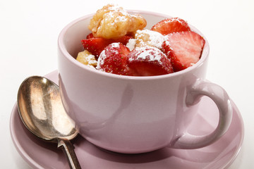 homemade kaiserschmarrn with strawberries and icing sugar in a cup