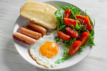 Breakfast which includes eggs, sausages, salad and toast with cheese