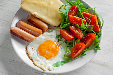 Breakfast which includes eggs, sausages, salad and toast with cheese