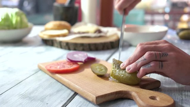 Male hands cutting pickle. Sliced vegetables on wood board. Vegetarian salad recipes.