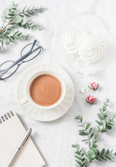 Coffee with milk, meringues, flowers, blank notebook, glasses on white background, top view. Female table inspiration breakfast, snack. Flat lay