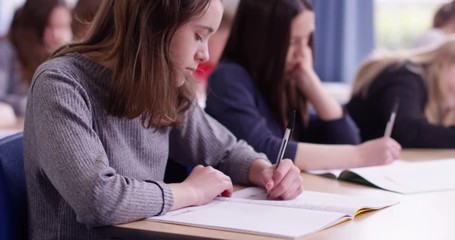 4k, Students in school uniform taking exam at desk in a classroom. Slow motion.