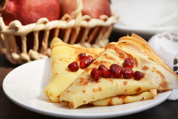 Thin pancakes ( crepes ) topped with pomegranate seeds. Healthy homemade breakfast. 