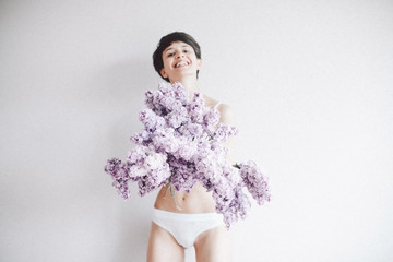 girl holds a bush of lilac flowers and smiling