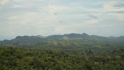 Vew Mountains with rainforest covered with green vegetation and trees on the tropical island, landscape. Mountains and hills with wild forest, sky clouds. Hillside rainforest and jungle. Philippines