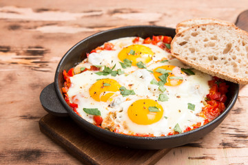 Tasty and Healthy Shakshuka in a Frying Pan. Fried eggs with tomatoes, bell pepper, vegetables and herbs. Middle eastern traditional dish.