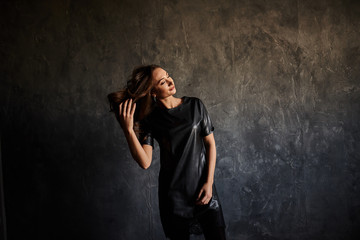 Portrait beautiful woman with elegant black dress. Pretty young woman standing against grunge background. Lady before evening party or meeting looking in window.