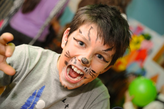 The young boy with a painted face roars like a lion and is preparing to attack