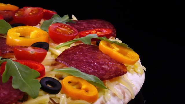 Closeup view of tasty homemade pizza rotating on black background in 4K
