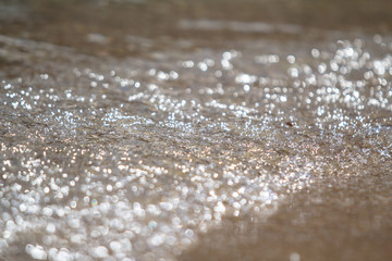 The bubbly sea foam and sand on the beach