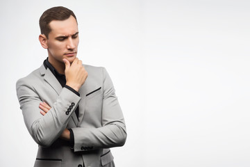 A young man wearing a gray suit thinking