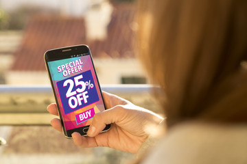 Girl holding a smartphone with a 25% discount advertising on the screen. Marketing, ecommerce, cell phone publicity.