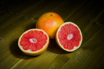 Grapefruit whole and halves on wooden background