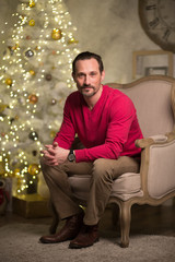 Fototapeta premium Young man with beard sitting in luxury arm chair. looking thoughtful.
