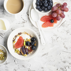 Seasonal healthy breakfast: yoghurt, chocolate granola, pink grapefruit, grapes, pistachios Top view Copy