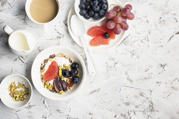 Seasonal healthy breakfast: yoghurt, chocolate granola, pink grapefruit, grapes, pistachios Top view Copy