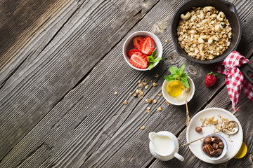 Homemade granola with cashew and fresh strawberries for a healthy homemade breakfast in a baking sheet on a wooden background. Top View.
