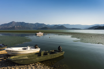  Boats on the shore of Shkoder Lake surrounded by mountains , Montenegro, Europe