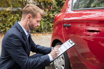 Insurance Agent Examining Car After Accident