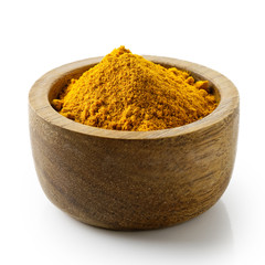 Turmeric powder in dark wood bowl isolated on white.