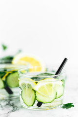glass with detox water, on a marble surface, with parsley, cucumber and lemon