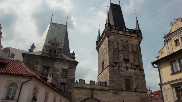 A walking shot down a old town Prague street looking up at the building facades and old cityscape, ancient huge tower, old multistoreyed building with an arc