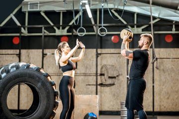 Young athletic couple in blacksportswear training with crossfit wall ball in the gym