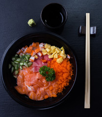 Japanese Tekka Don (Seafood, Raw Salmon, Tuna, Otoro, Shrimp, Scallop on Rice) on dark background. Top view with copy space.