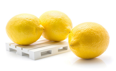 Three yellow lemons isolated on white background two lemons on a pallet.