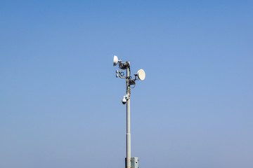 Security and satellite system with a surveillance camera, antenna and communications dishes on a...