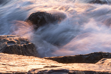Waves break on the rocks at dawn.
